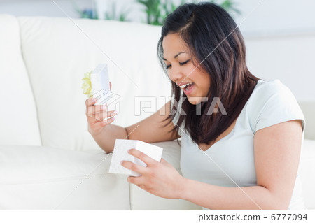 Woman smiling while looking at an open gift box Woman smiling while looking at an open gift box 6777094