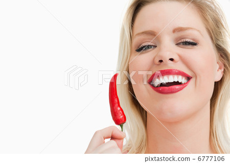 Blonde woman holding a chili while laughing Blonde woman holding a chili while laughing 6777106