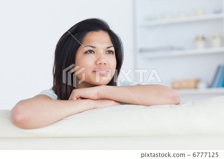 Thinking woman crossing her arms as she stands on a white couch Thinking woman crossing her arms as she stands on a white couch 6777125