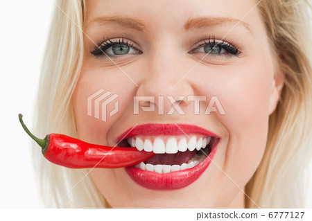 Happy blonde woman biting a red chili pepper Happy blonde woman biting a red chili pepper 6777127