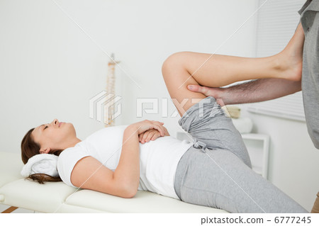 Woman putting her foot on the chest of her doctor while stretchi Woman putting her foot on the chest of her doctor while stretchi 6777245