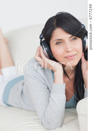Woman wearing headphones and laying on a couch Woman wearing headphones and laying on a couch 6777249