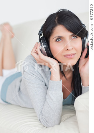 Woman laying on a couch while wearing headphones on Woman laying on a couch while wearing headphones on 6777250