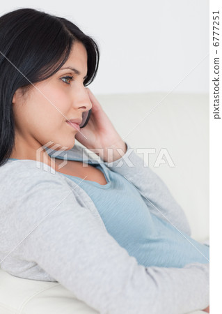 Woman with a phone in her hand while sitting on a couch 6777251