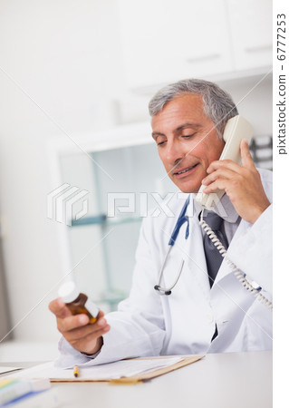 Doctor holding a drug box and a phone 6777253