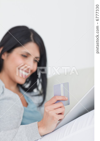Woman looking at a tactile tablet while holding a credit card Woman looking at a tactile tablet while holding a credit card 6777330