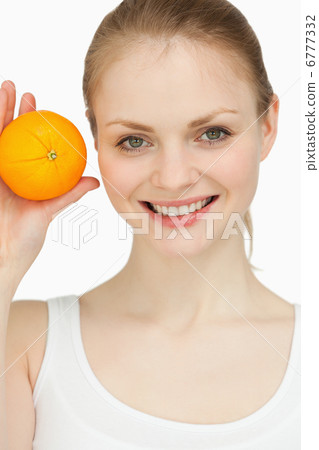 Smiling blonde-haired presenting an orange Smiling blonde-haired presenting an orange 6777332