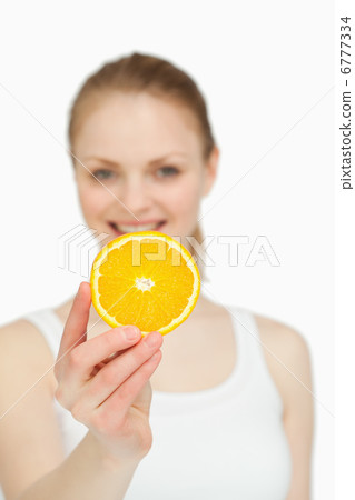 Woman presenting an orange slice while smiling Woman presenting an orange slice while smiling 6777334
