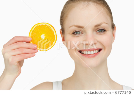 Cheerful woman holding a slice of orange Cheerful woman holding a slice of orange 6777340