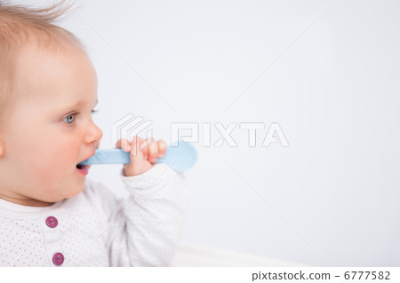 Cute baby biting a blue spoon 6777582