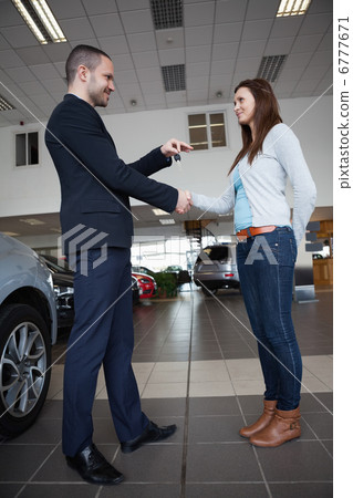Salesman giving car keys while shaking hand of a client Salesman giving car keys while shaking hand of a client 6777671