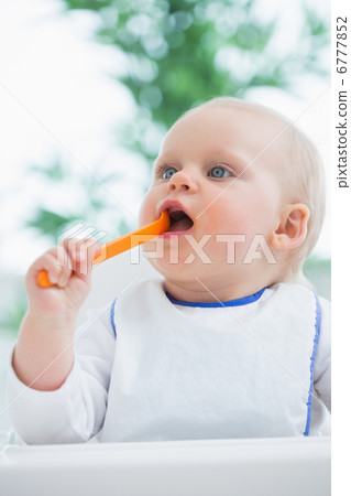 Baby holding a plastic spoon while putting it in his mouth Baby holding a plastic spoon while putting it in his mouth 6777852