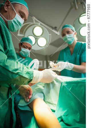 Team of surgeons operating the arm of a patient 6777988