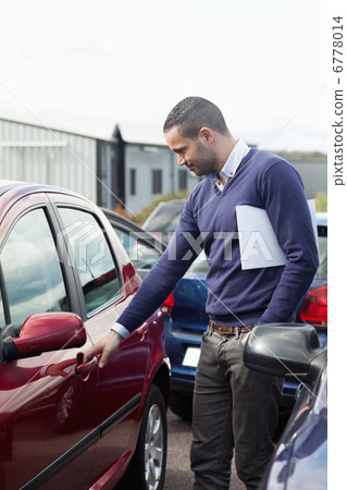 Man looking at a car door while opening it 6778014