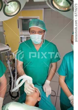 Surgeon placing an oxygen mask on the face of a patient 6778273