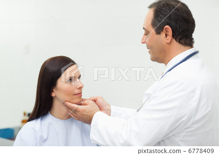 Doctor auscultating the neck of a patient 6778409