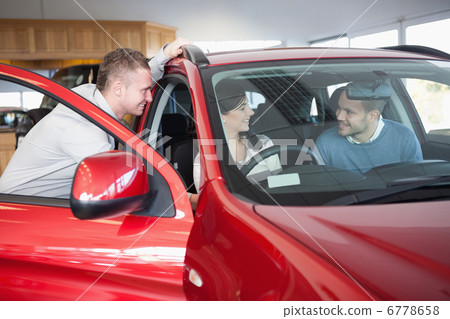 Couple listening to a salesman while sitting on a car 6778658