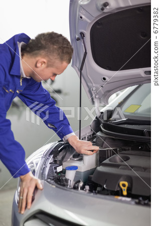 Concentrated mechanic looking at an engine Concentrated mechanic looking at an engine 6779382