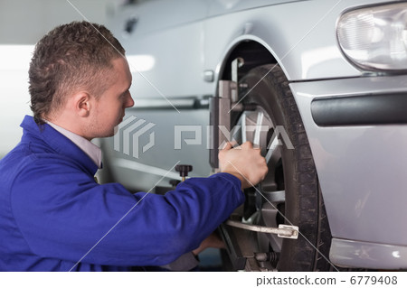 Concentrated mechanic repairing a car wheel Concentrated mechanic repairing a car wheel 6779408