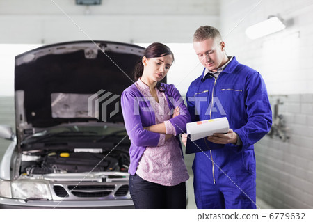 Mechanic showing a clipboard to a client Mechanic showing a clipboard to a client 6779632