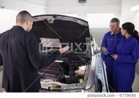 Client looking at a car next to mechanics Client looking at a car next to mechanics 6779698
