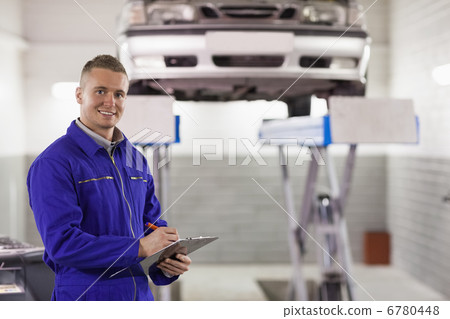 Smiling mechanic holding a clipboard while looking at camera Smiling mechanic holding a clipboard while looking at camera 6780448