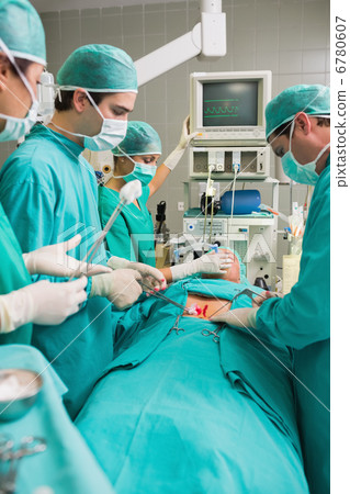 Side view of a surgical team next to a patient 6780607
