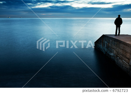 Man is standing on a jetty looking the sunset 6792723