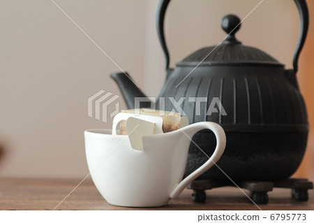 A single-serving drip coffee in a coffee cup and an iron kettle 6795773