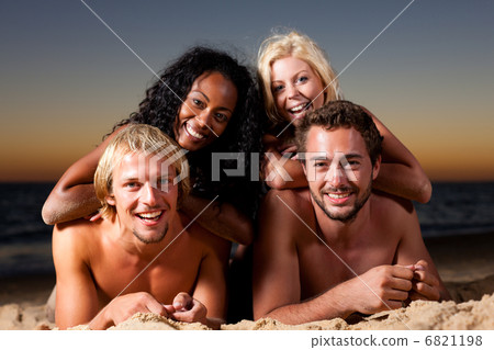 Four friends at the beach with sunset 6821198