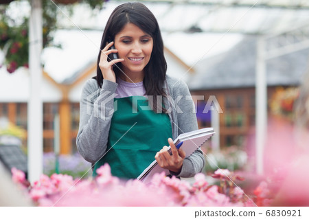 Garden center worker phoning while taking notes Garden center worker phoning while taking notes 6830921