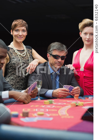Man in sunglasses smiling at poker table Man in sunglasses smiling at poker table 6832140