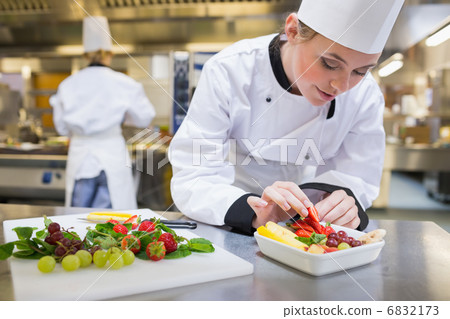 Chef putting a strawberry in the fruit salad 6832173