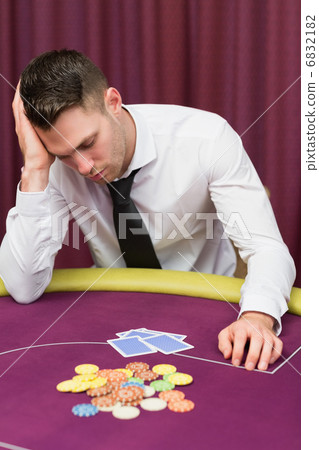 Man leaning on poker table looking disappointed Man leaning on poker table looking disappointed 6832182