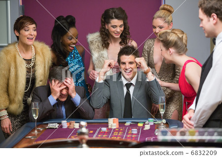 Man winning as another is losing at roulette table 6832209