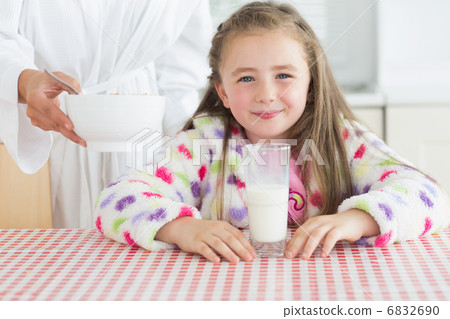 Happy little girl with glass of milk getting cereal from her mot Happy little girl with glass of milk getting cereal from her mot 6832690