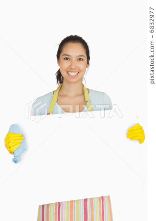 Woman in apron and rubber gloves holding white surface 6832977