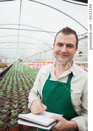 Smiling man taking notes in greenhouse 6833149