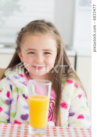 Little girl sitting while smiling with glass of orange juice Little girl sitting while smiling with glass of orange juice 6833477