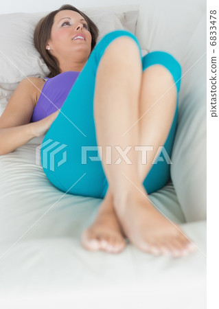 Happy woman lying on sofa looking away Happy woman lying on sofa looking away 6833478