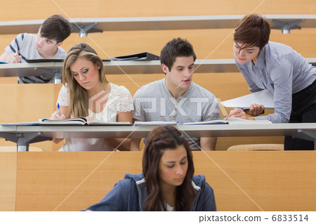 Students sitting at the lecture hall while teacher explaining 6833514