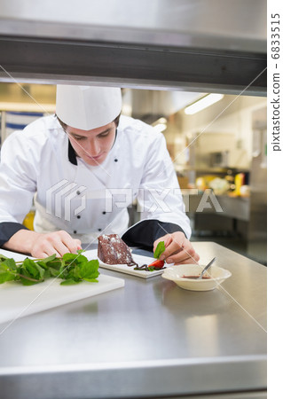 Chef putting mint leaf with cake 6833515
