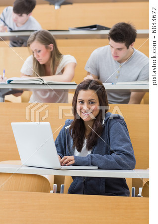 Smiling student in lecture with laptop 6833672