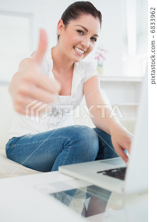 Woman using a laptop and giving thumbs up 6833962