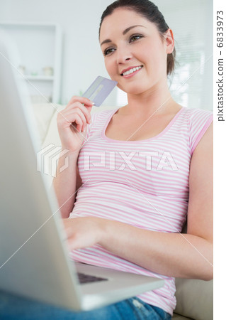 Woman sitting on a couch with a laptop and a credit card Woman sitting on a couch with a laptop and a credit card 6833973