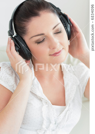 Woman listening to music and sitting on the couch 6834096