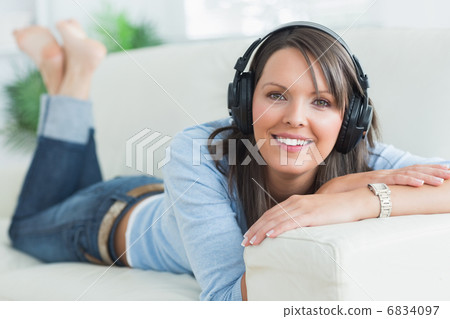 Woman listening music looking happy on sofa Woman listening music looking happy on sofa 6834097