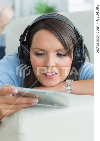 Woman listening music and looking at cd on sofa Woman listening music and looking at cd on sofa 6834098