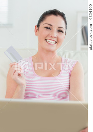 Woman sitting on a couch with a laptop and a credit card 6834100
