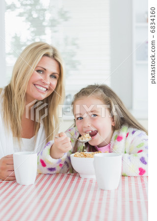 Little girl eating cereal at breakfast with her mother Little girl eating cereal at breakfast with her mother 6834160